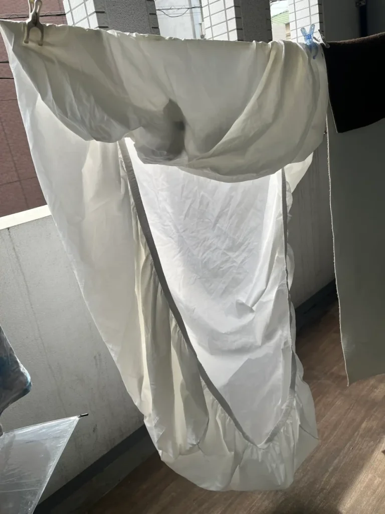 防水シーツを物干しに広げて干している実物写真。防水面に風を当てて乾かしている様子