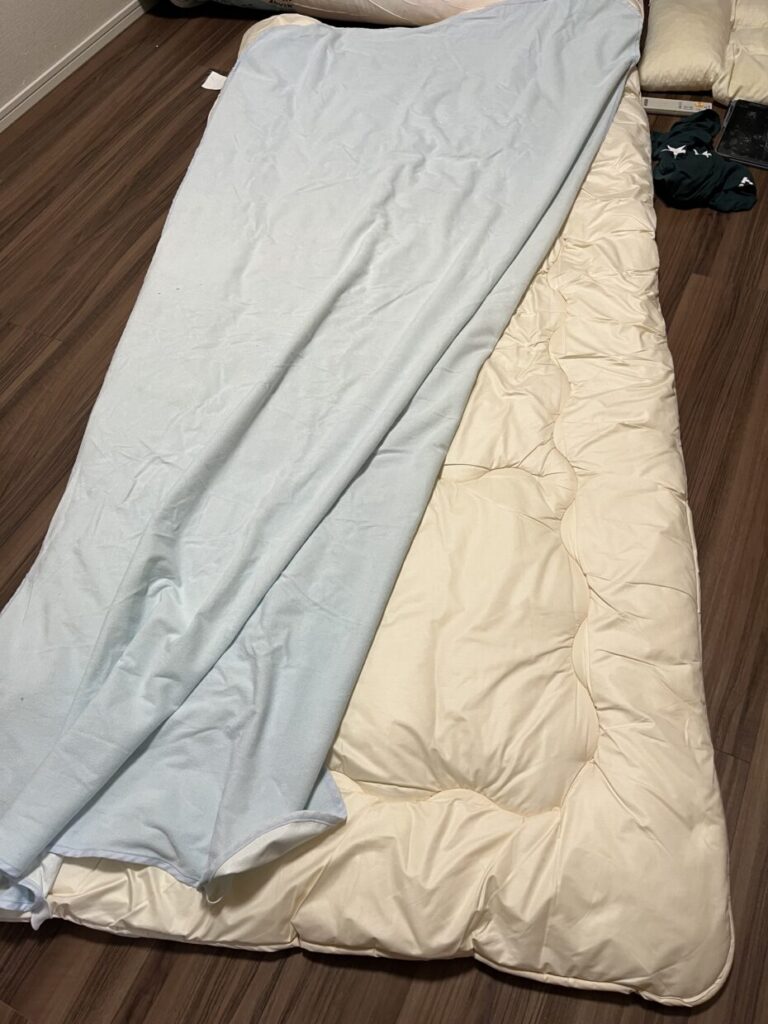 四隅ゴムタイプの防水シーツがズレて、布団の端がむき出しになっている実物写真