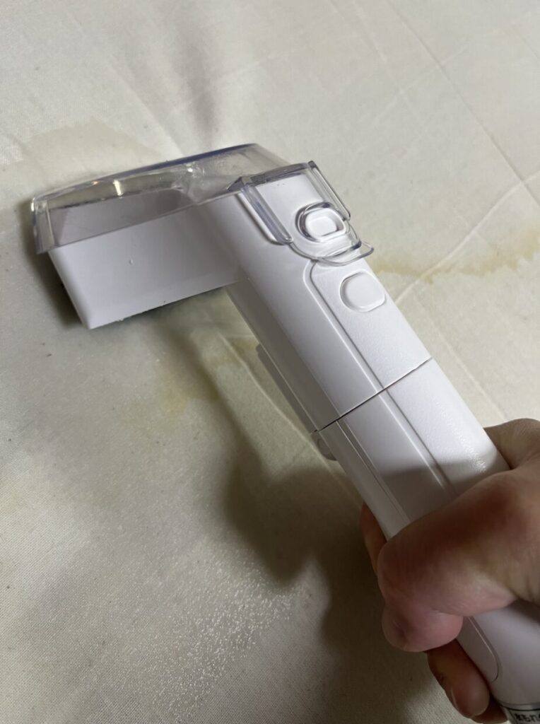 布製ソファの座面クッションへリンサークリーナーのノズルを当てて掃除している様子
