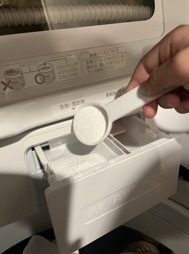 粉末ナチュウォッシュを計量スプーンで洗剤ケースへ入れている様子