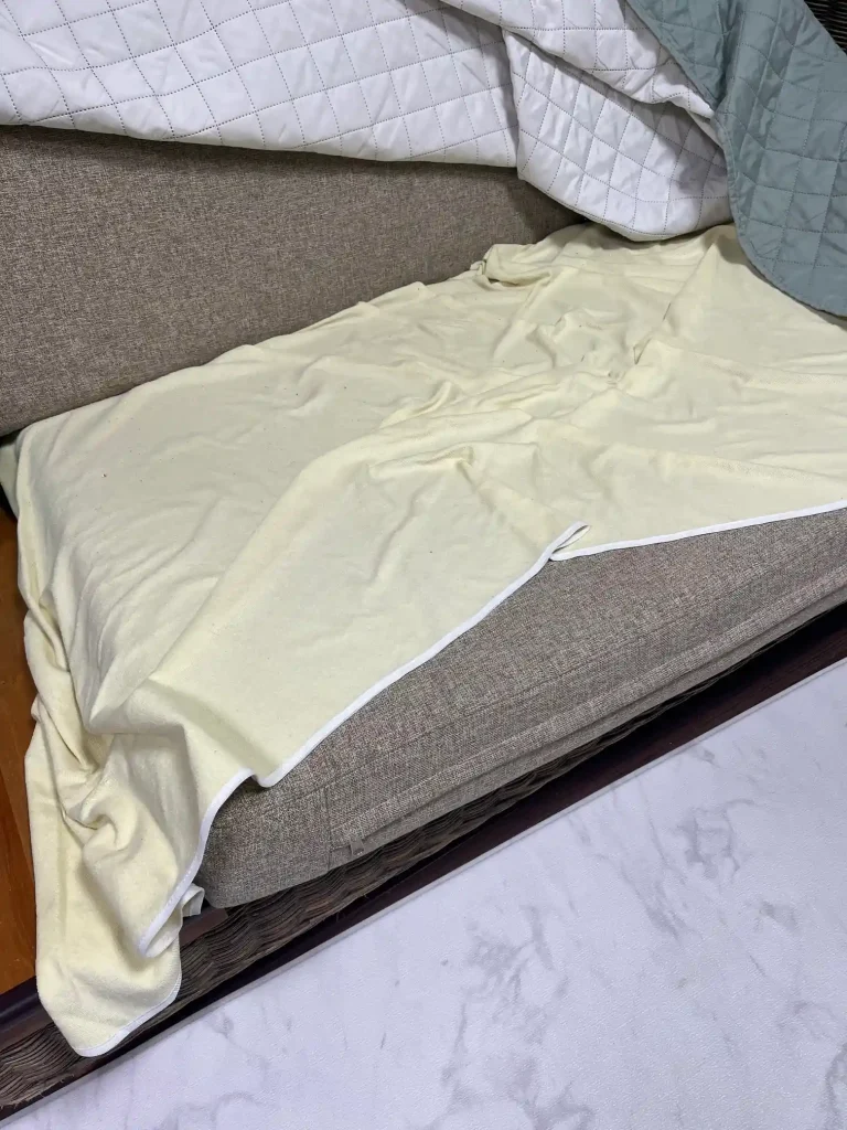 四隅バンド式の防水シーツがずれ、布製ソファの座面が露出している様子