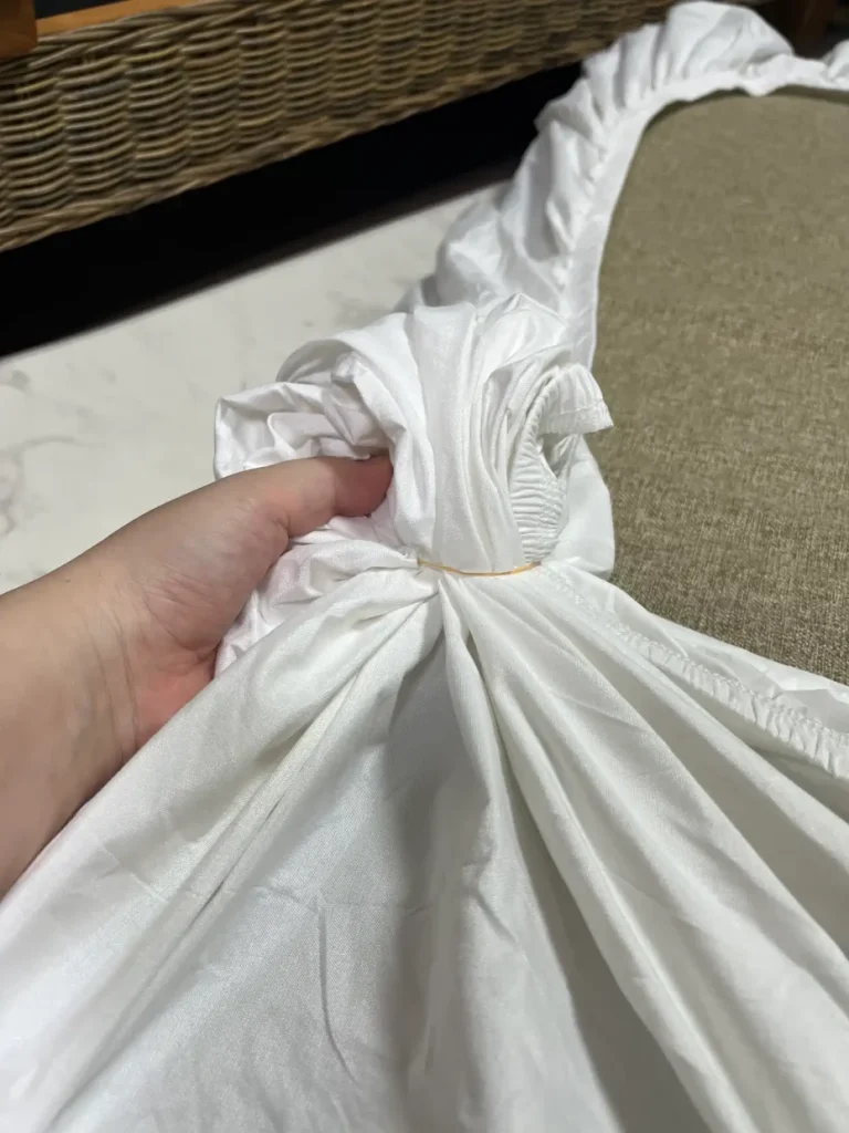 側面まで覆う防水ボックスシーツの全周ゴム部分を手で持っている様子