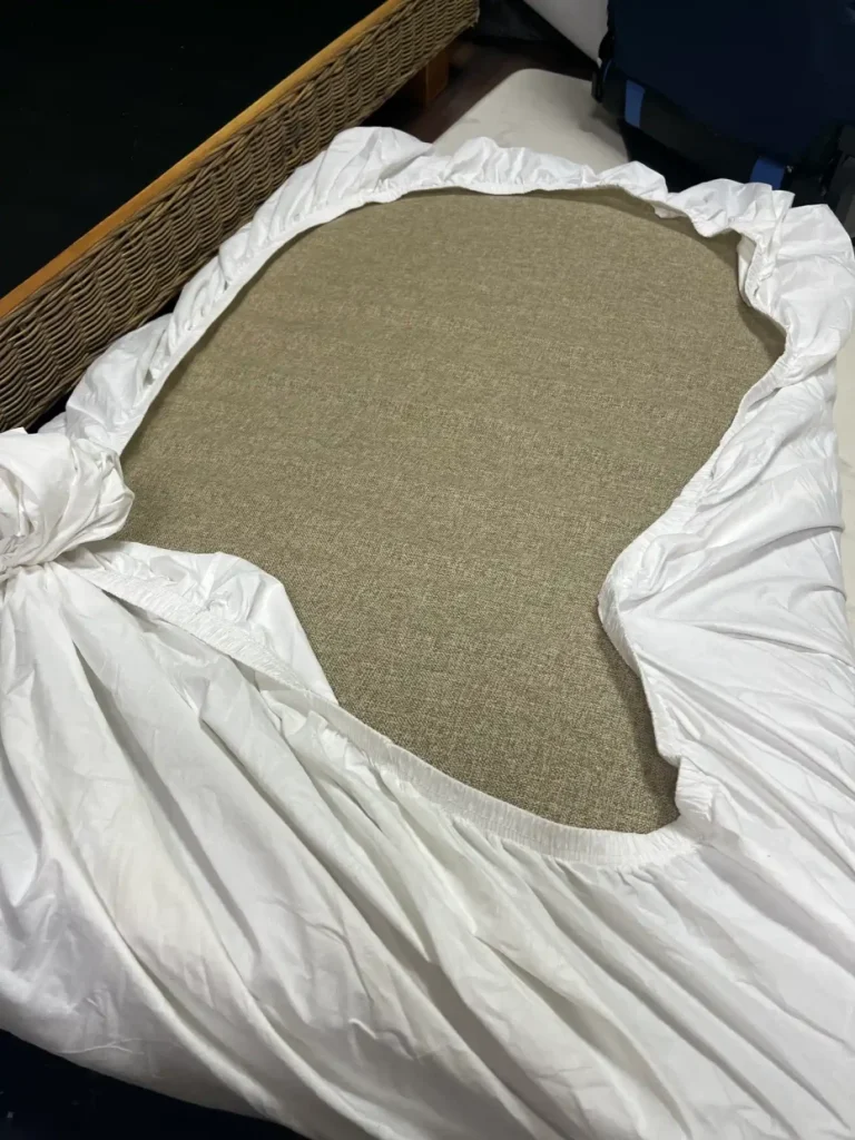 大きなソファの座面クッションへ防水ボックスシーツを掛けている途中