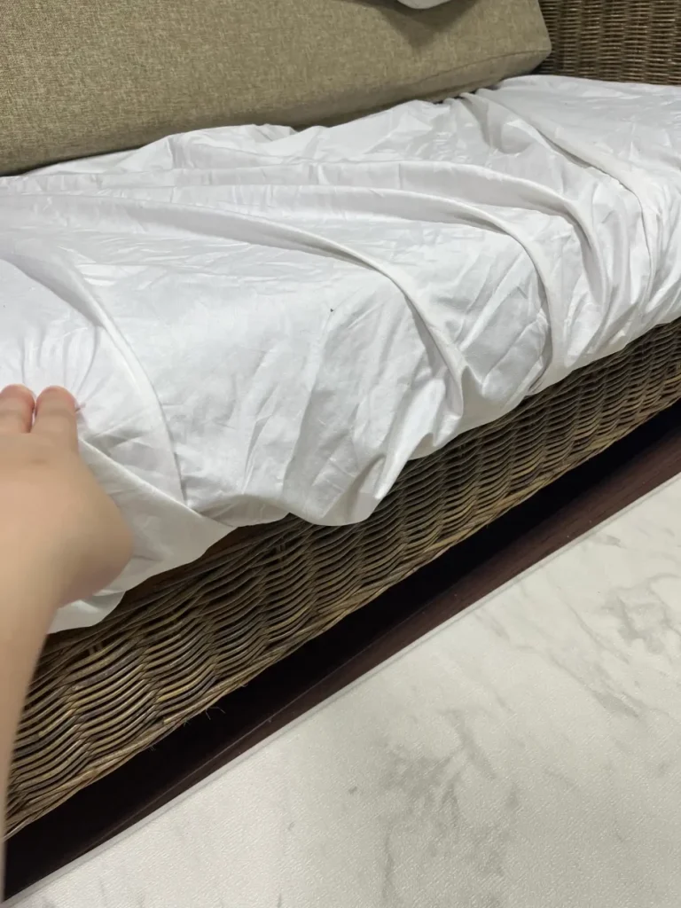 完全防水シーツを掛けた座面クッションをソファ本体へ戻している様子