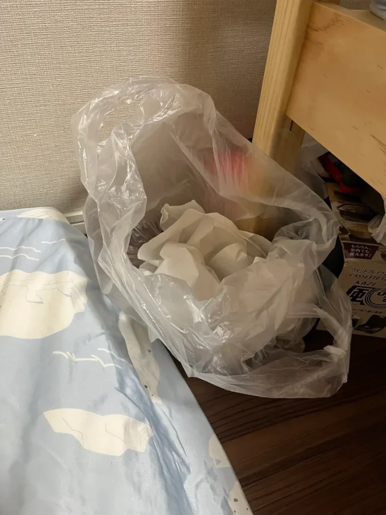 保護者がすぐ取れるフローリングへ置いた持ち手付き嘔吐用袋の再現写真