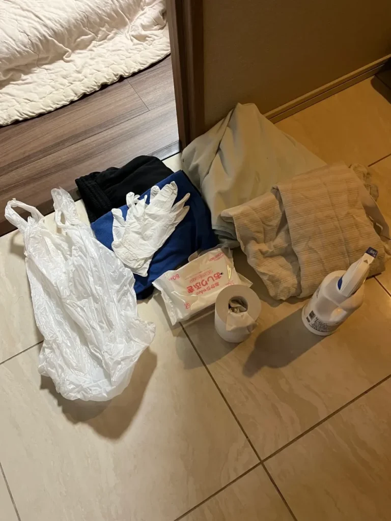 子どもの夜中の嘔吐に備えて寝室入口へ置いた袋、手袋、着替え、シーツなどのセット