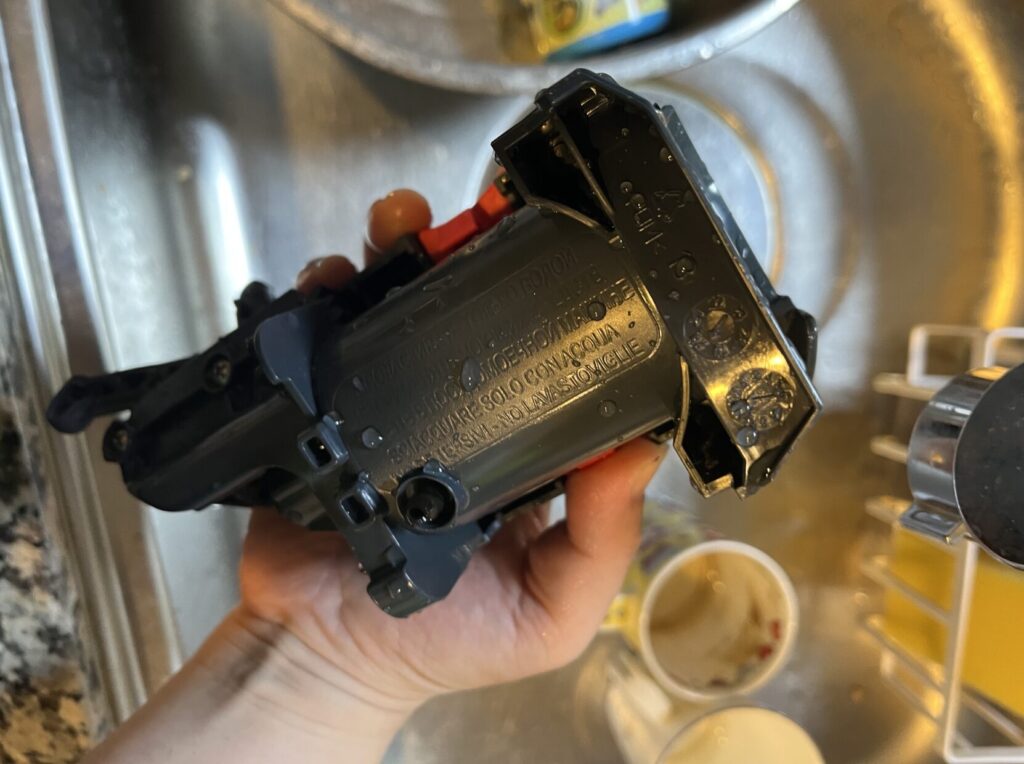 デロンギ プリマドンナXSの抽出ユニットを洗剤を使わず流水ですすいでいる様子